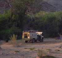 A vehicle is parked , camped, in the bed of the Hoanib River in Namibia